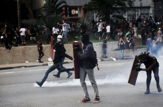 Demonstrator protester kicks a teargas canister fired by riot police during a protest against fare hikes for city buses in Sao Paulo
