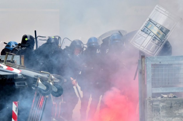 Italian riot police protect themselves from projectiles thrown by "No border" activists during clashes at the Brenner train station on May 7, 2016 during demonstrations against Austria's possible decision to close the border with Italy. Vienna is threatening to resume checks on the Brenner Pass between the two countries as part of a package of anti-migrant measures if Italy does not do more to reduce the number of new arrivals heading to Austria. / AFP PHOTO / GIUSEPPE CACACE